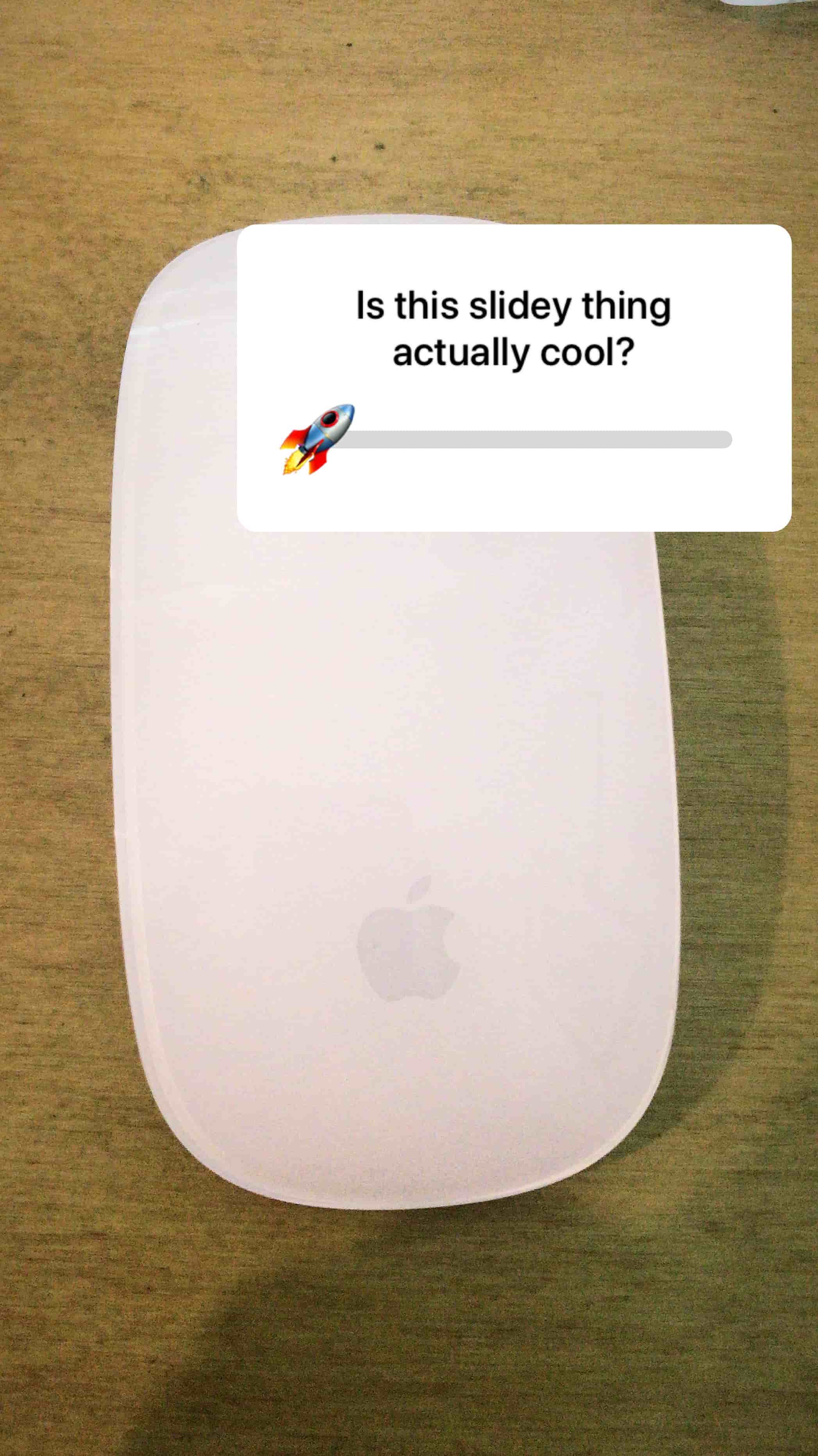 white apple mouse on desk with rocket emoji on emoji slider and text saying is this slidey thing actually cool?