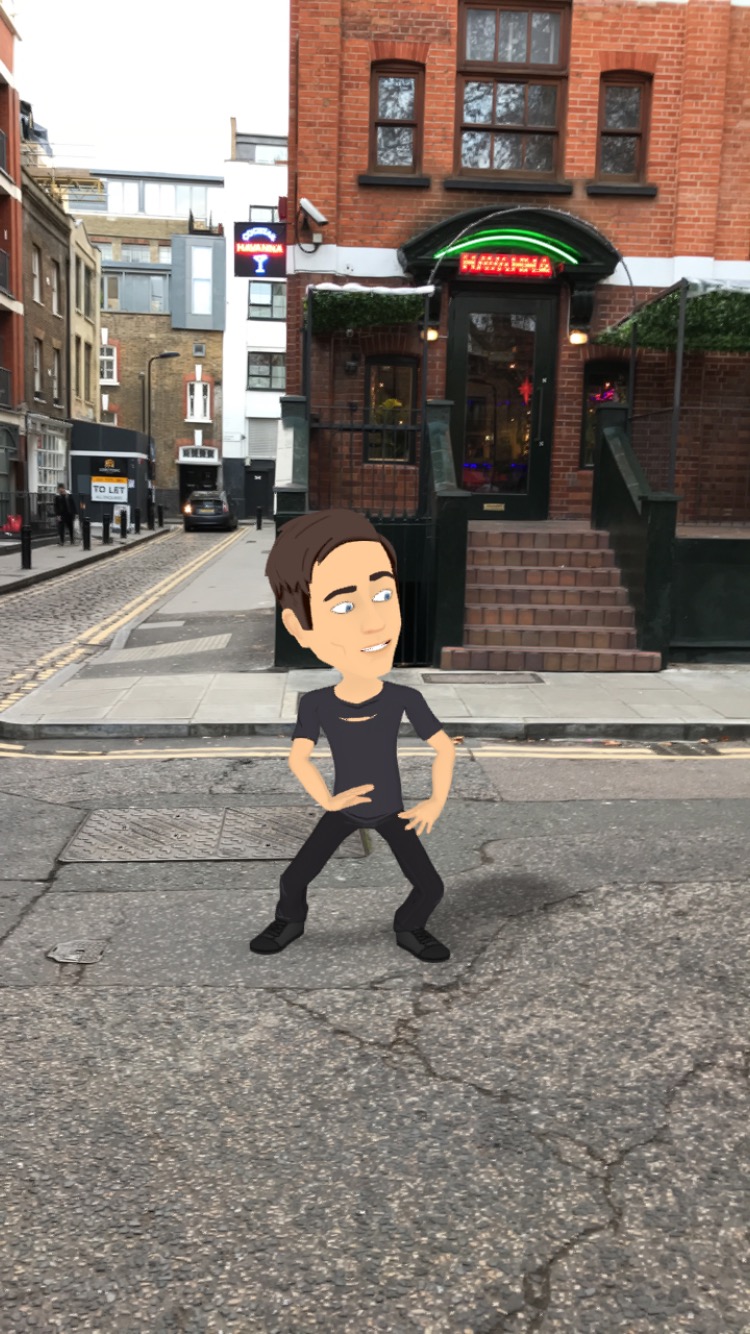 Cartoon version of brown-haired white male author dancing on the road in front of a face-brick cocktail bar in Hoxton Square, London